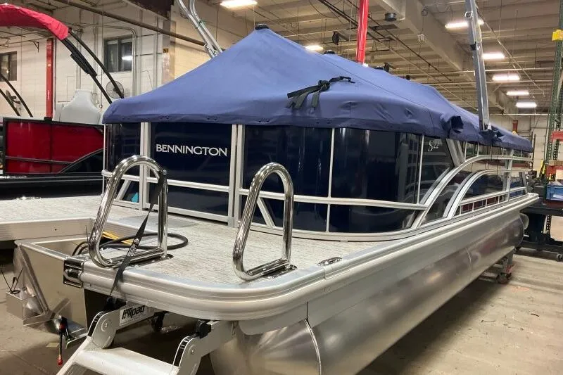 Slide: The Image of 2026 Bennington 22 SSRSE pontoon boat with blue cover in indoor showroom. - 11