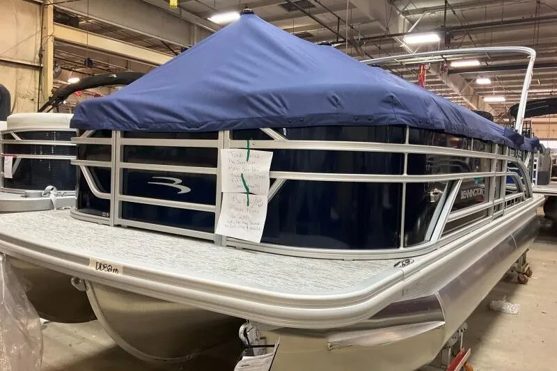 Slide: The Image of 2026 Bennington 22 SSRSE pontoon boat with blue cover in a warehouse setting. - 12