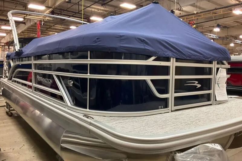 Slide: The Image of 2026 Bennington 22 SSRSE pontoon boat with blue cover in a warehouse setting. - 13