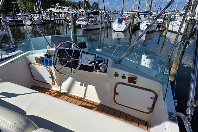 Slide: The Image of 1983 Bertram 28 Flybridge Cruiser helm at marina, surrounded by docked boats. - 15