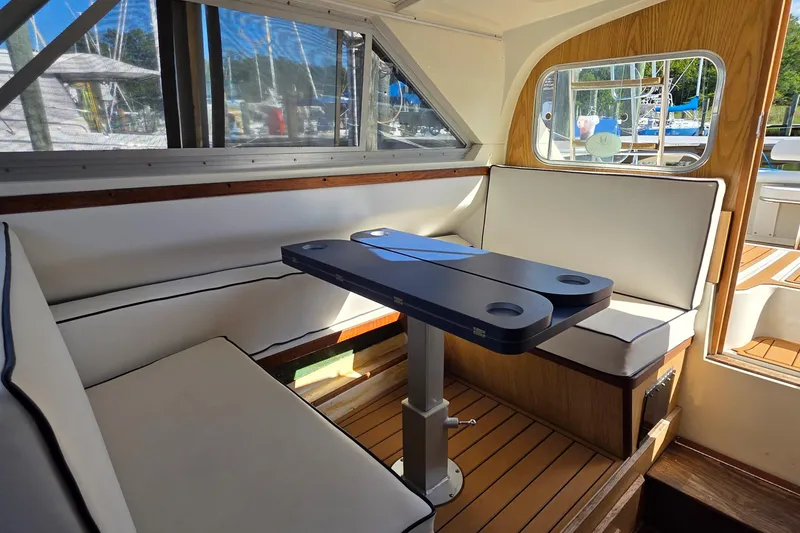 Slide: The Image of Interior of 1983 Bertram 28 Flybridge Cruiser with seating and table, featuring wood accents. - 17