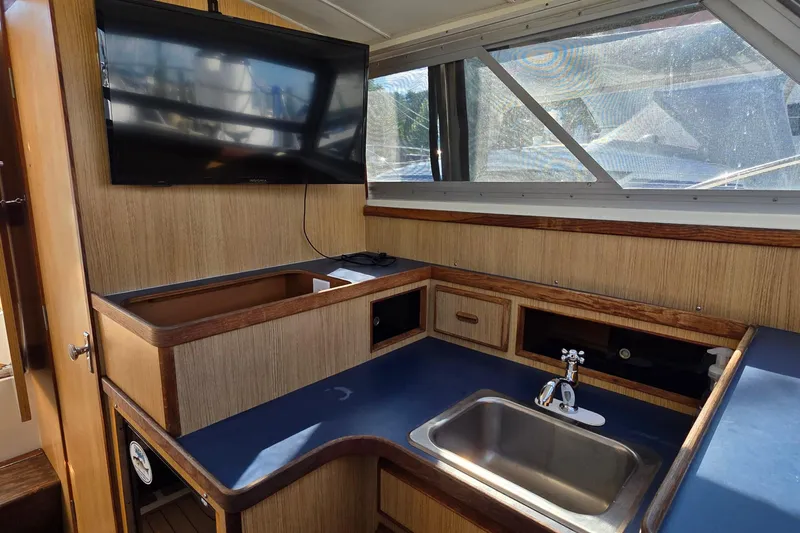 Slide: The Image of Interior of 1983 Bertram 28 Flybridge Cruiser with sink, counter, and mounted TV. - 22