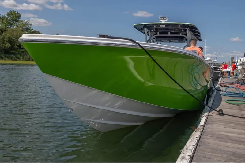 Slide: The Image of 2014 Nor-Tech 390 Sport Cuddy Center Console in vibrant green docked by the water. - 15