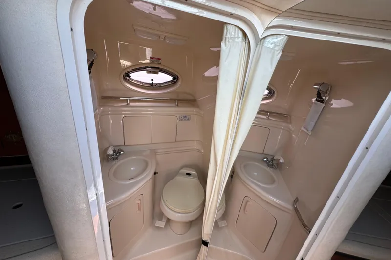 Slide: The Image of Compact bathroom in 2003 Sea Ray 280 Sundancer boat with sink, toilet, and porthole window. - 10