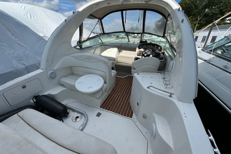 Slide: The Image of 2003 Sea Ray 280 Sundancer boat interior with seating and helm, docked under clear skies. - 4