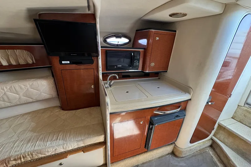 Slide: The Image of 2003 Sea Ray 280 Sundancer interior with kitchenette, TV, and cozy sleeping area. - 9