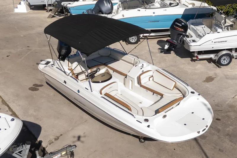 Slide: The Image of 2024 Stingray 192 SC boat with black canopy, parked on concrete, surrounded by other boats. - 4