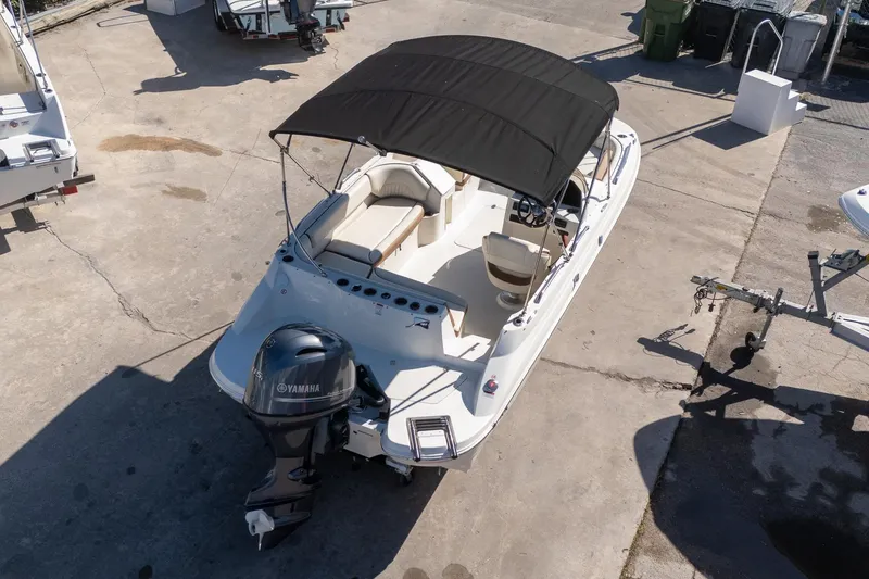 Slide: The Image of 2024 Stingray 192 SC boat with Yamaha outboard motor and black canopy, parked on concrete. - 5