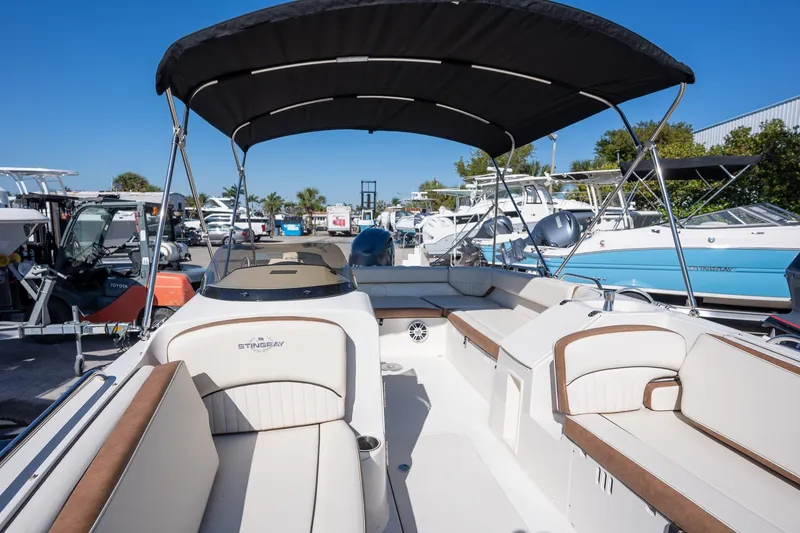 Slide: The Image of 2024 Stingray 192 SC boat interior with seating and canopy in a marina setting. - 7