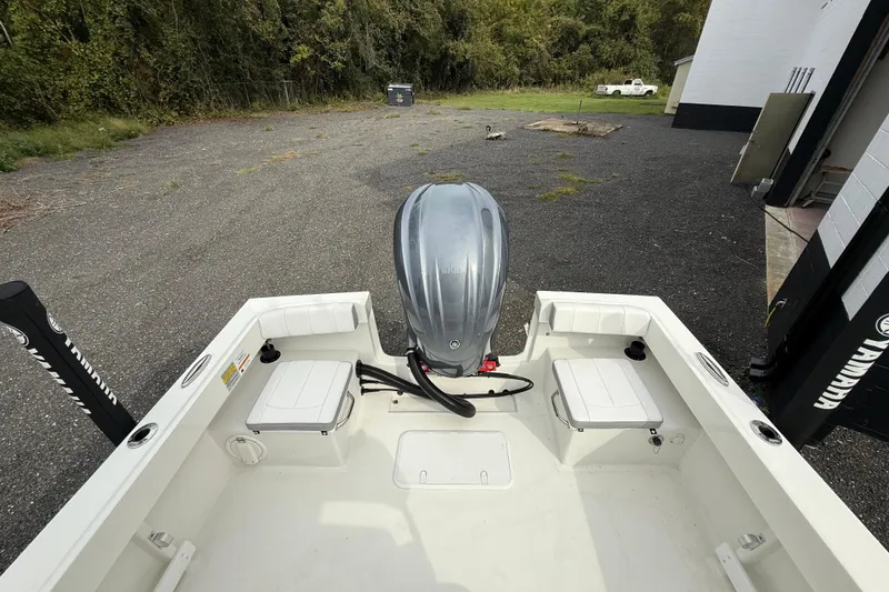 Slide: The Image of 2024 Parker 2300 Special Edition boat with outboard motor, parked on gravel near trees. - 9