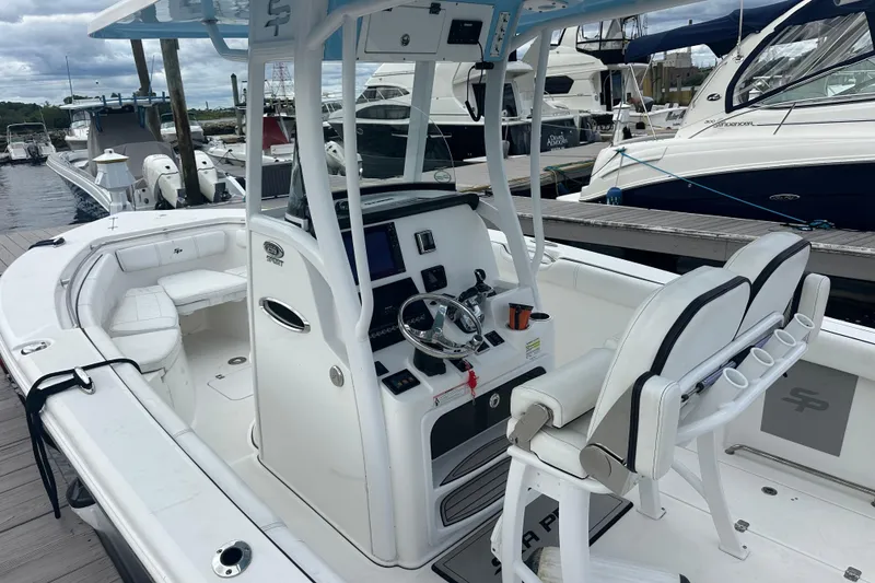 Slide: The Image of 2020 Sea Pro 259 Sport boat interior at marina, featuring helm and seating. - 6