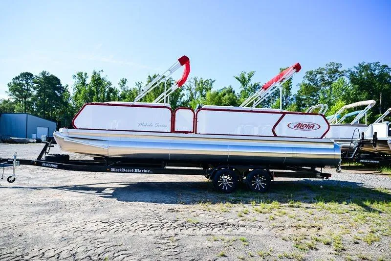 The Image of 2023 Aloha Pontoon Mahalo 23 boat on trailer, outdoors, with trees in background. - 0