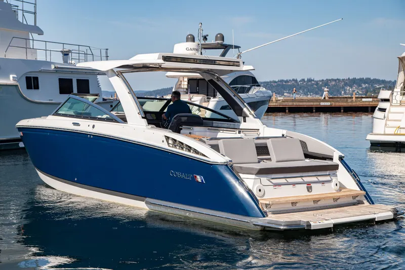 Slide: The Image of 2023 Cobalt R33 boat docked in marina, featuring sleek blue and white design. - 11