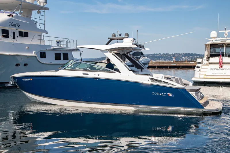 Slide: The Image of 2023 Cobalt R33 boat docked in marina, featuring sleek blue and white design. - 12