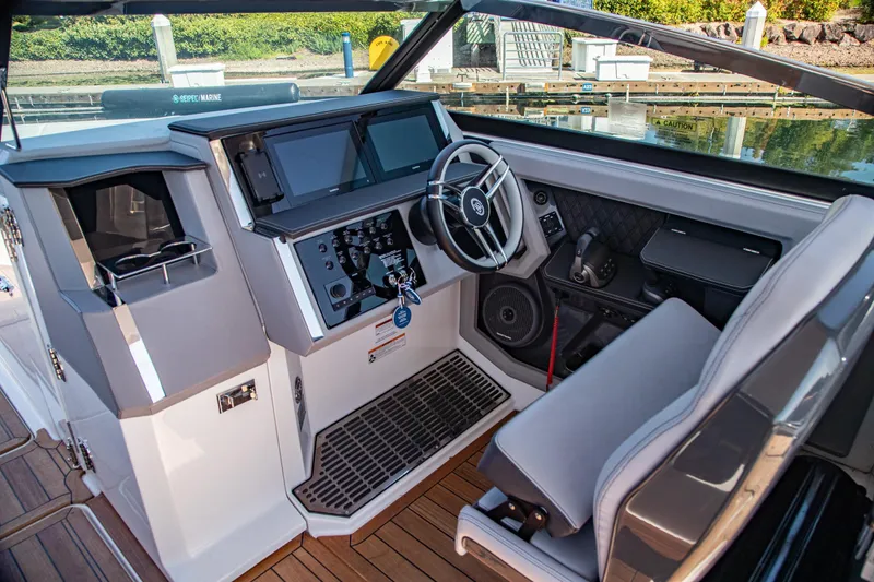 Slide: The Image of 2023 Cobalt R33 boat cockpit with modern steering, controls, and dashboard at a marina. - 26