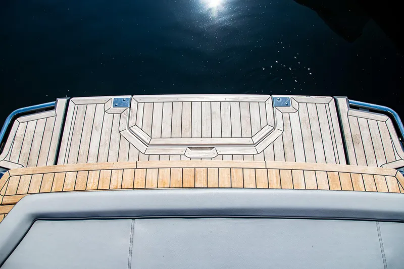 Slide: The Image of 2023 Cobalt R33 boat deck with wooden finish, reflecting sunlight on water. - 38