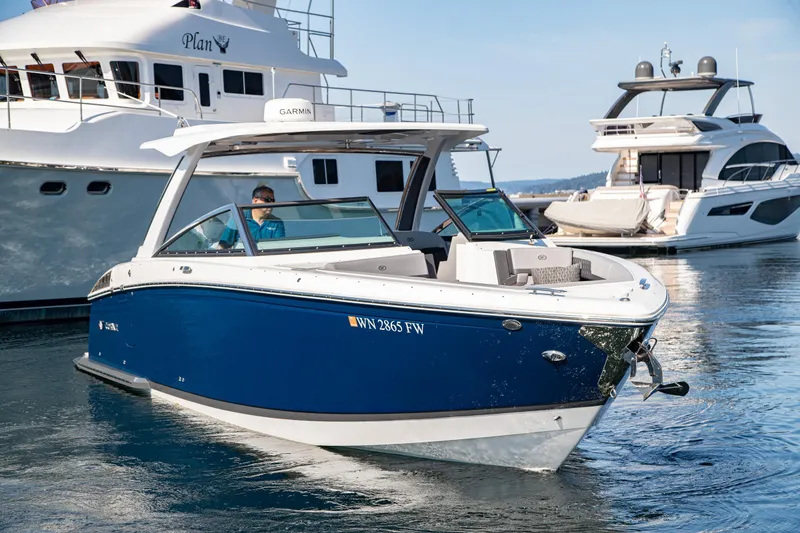 Slide: The Image of 2023 Cobalt R33 boat cruising in marina, surrounded by luxury yachts. - 4