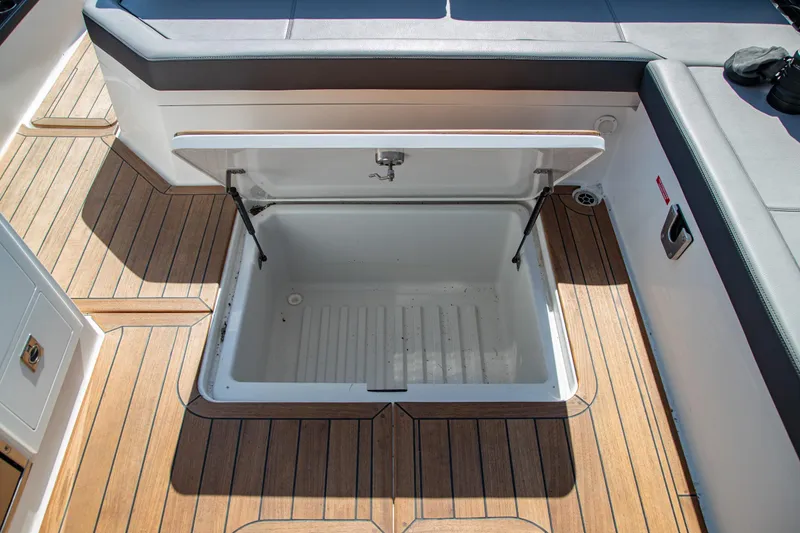 Slide: The Image of Open storage compartment on 2023 Cobalt R33 boat with teak flooring. - 48