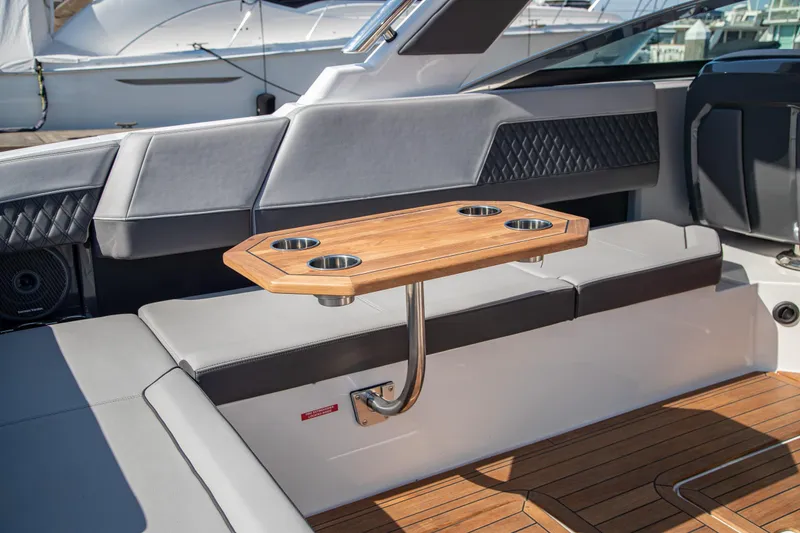 Slide: The Image of Luxury seating area on 2023 Cobalt R33 boat with wooden table and cup holders. - 57