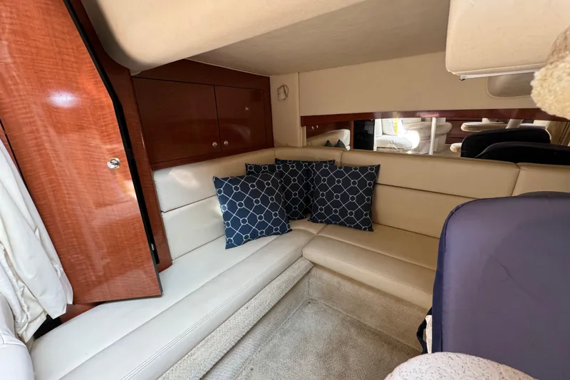 Slide: The Image of Interior of 2003 Sea Ray 320 Sundancer with beige seating and blue patterned cushions. - 12