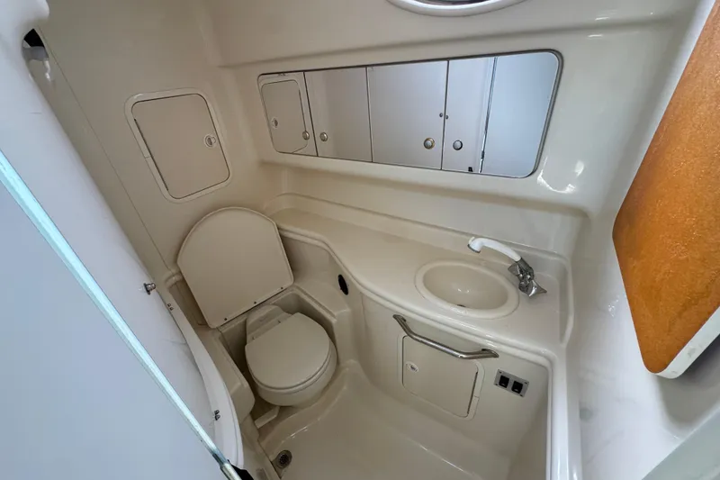 Slide: The Image of 2003 Sea Ray 320 Sundancer bathroom with toilet, sink, and storage cabinets. - 13