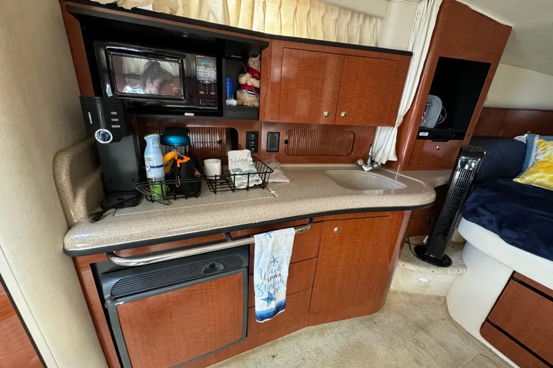 Slide: The Image of 2003 Sea Ray 320 Sundancer cabin with kitchenette, microwave, sink, and cozy sleeping area. - 9