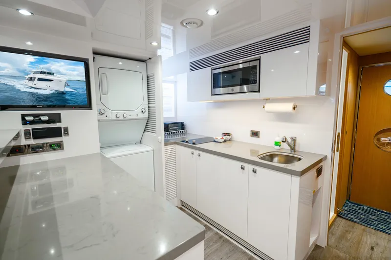 Slide: The Image of Modern yacht kitchen with appliances, featuring a washer-dryer, microwave, and sleek countertops. Horizon FD80, 2020. - 20