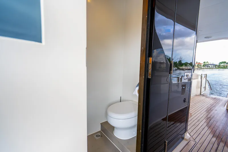 Slide: The Image of 2020 Horizon FD80 yacht bathroom with open door, overlooking water and deck. - 25