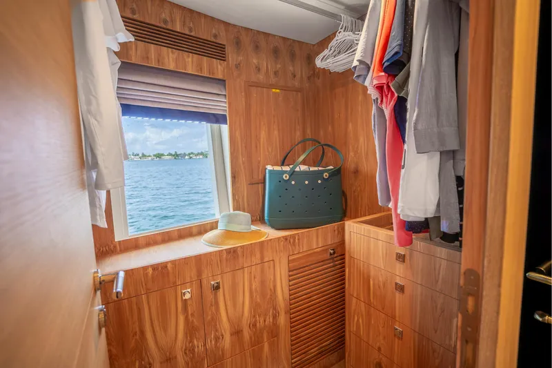 Slide: The Image of Luxurious Horizon FD80 yacht closet with ocean view, wooden cabinetry, and hanging clothes. - 26