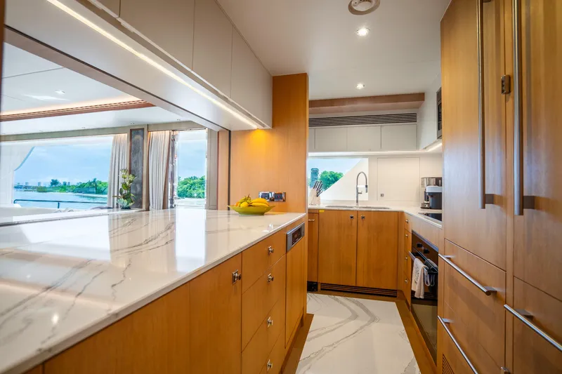 Slide: The Image of Luxurious Horizon FD80 yacht kitchen with modern wood cabinetry and marble countertops, 2020 model. - 28