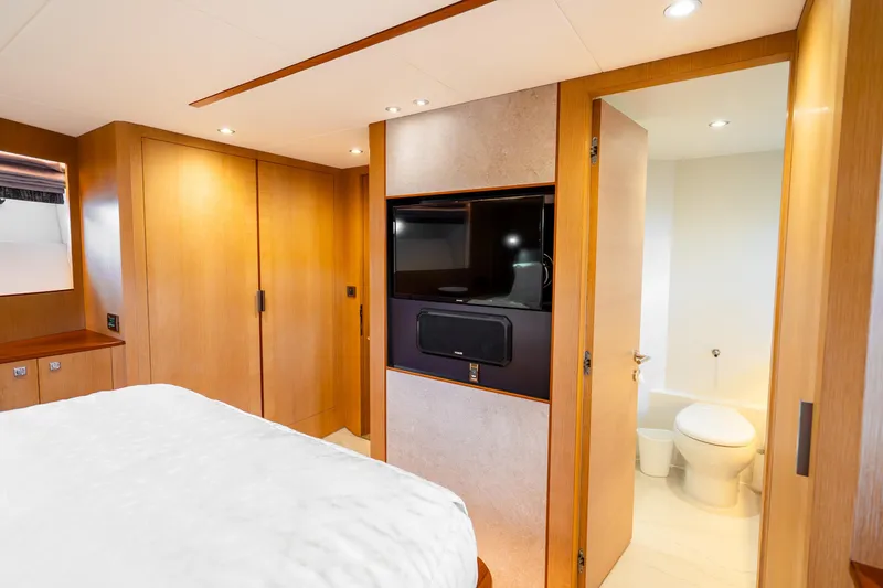 Slide: The Image of Luxurious Horizon FD80 yacht bedroom with ensuite bathroom, modern wood finishes, and built-in TV. - 44