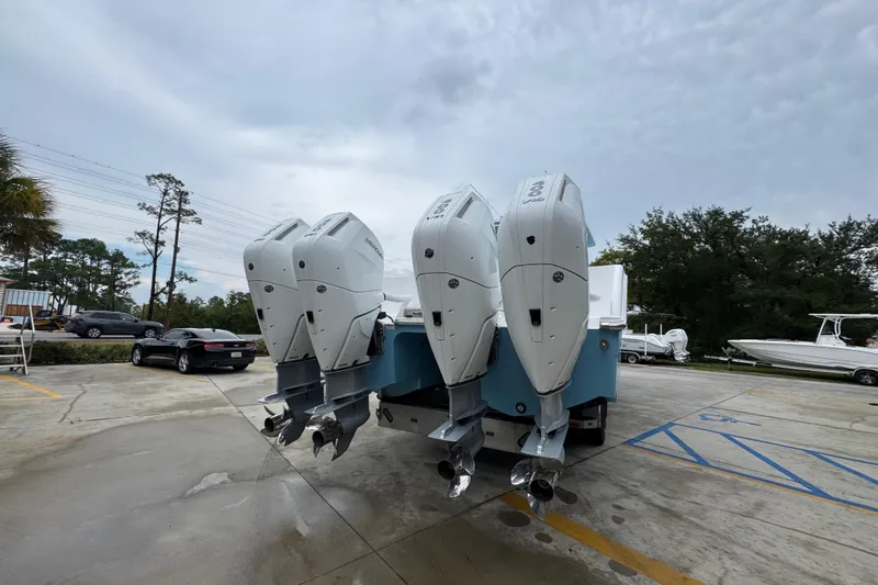 Slide: The Image of 2025 Invincible 40 Catamaran with triple outboard engines in a parking lot. - 16