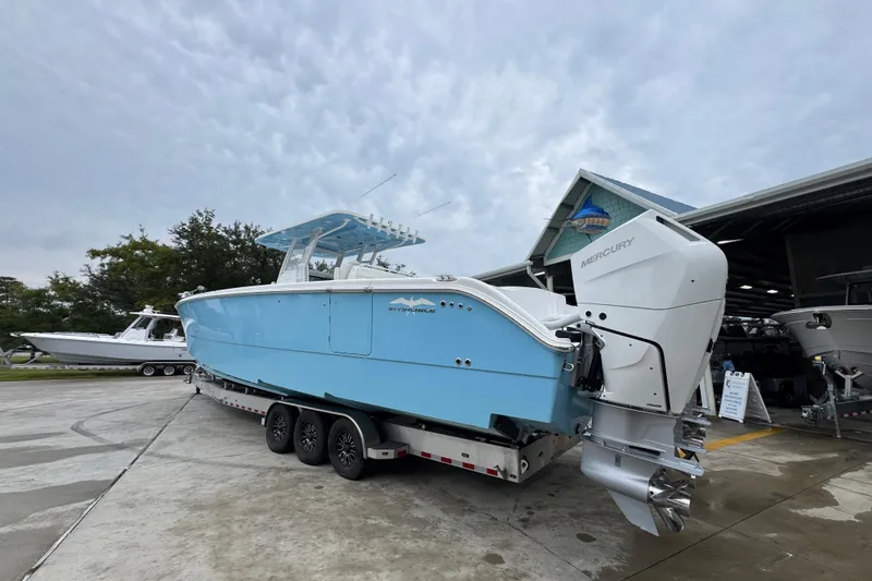 Slide: The Image of 2025 Invincible 40 Catamaran with Mercury engines on a trailer, parked outdoors. - 19