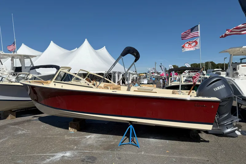 The Image of 2026 Rossiter 23 Open Bow boat displayed at a marine exhibition with flags and tents. - 1