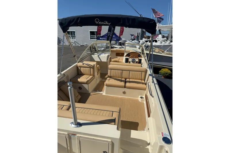 Slide: The Image of 2026 Rossiter 23 Open Bow boat with tan seating and canopy, docked at marina. - 5