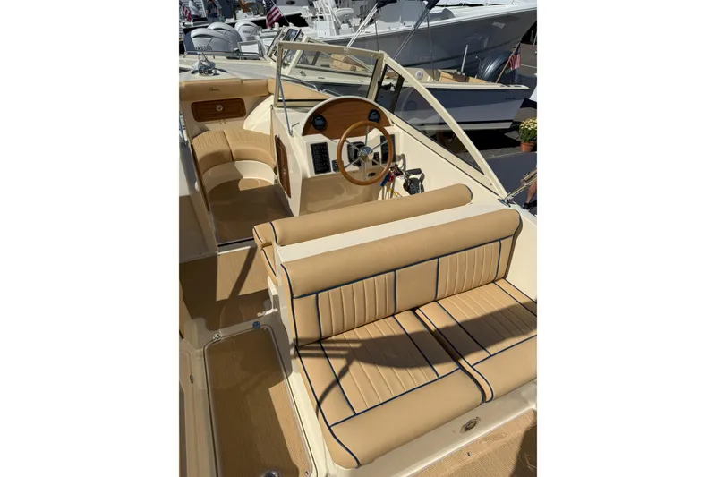 Slide: The Image of 2026 Rossiter 23 Open Bow boat interior with tan seating and wooden steering wheel. - 6
