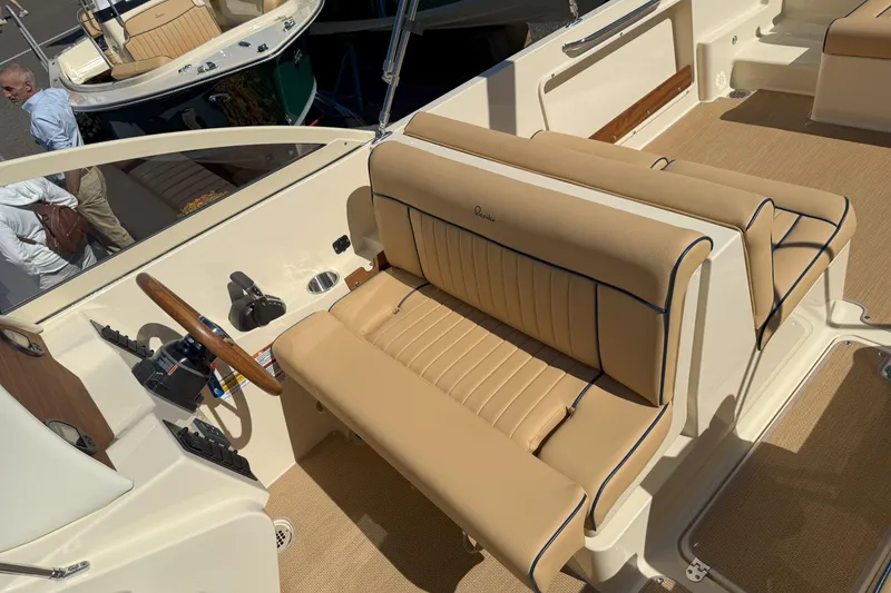 Slide: The Image of 2026 Rossiter 23 Open Bow boat interior with tan seating and wooden steering wheel. - 9