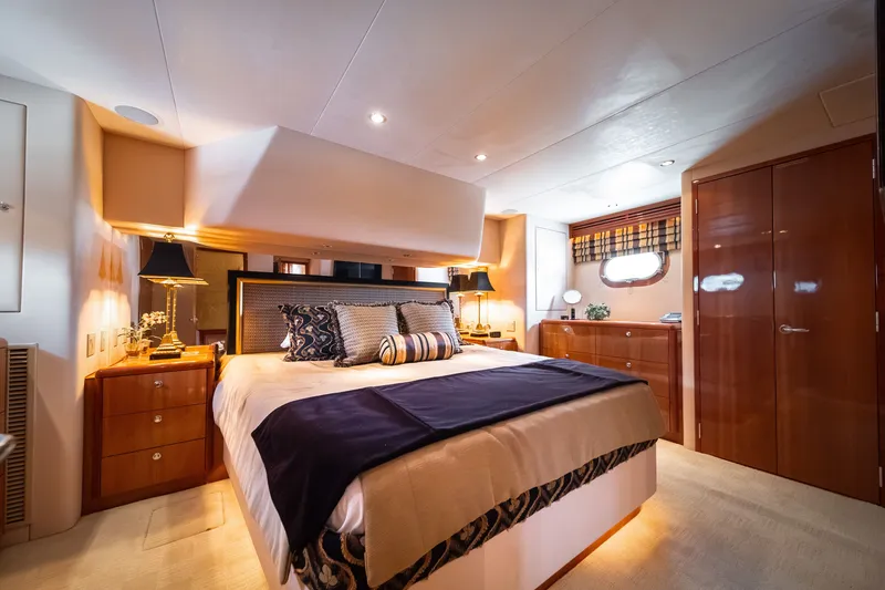 Slide: The Image of Luxurious bedroom with double bed, wooden furniture, and soft lighting on a Hatteras 64 Motor Yacht. - 19