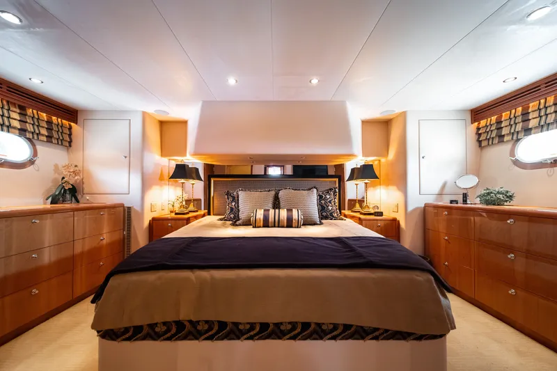 Slide: The Image of Luxurious bedroom with a large bed, wooden furniture, and stylish lamps on a Hatteras 64 Motor Yacht. - 18