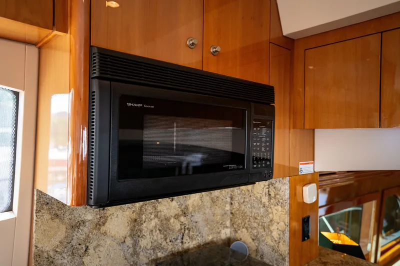 Slide: The Image of The 2008 Hatteras 64 Motor Yacht's kitchen features a microwave and wooden cabinets. - 37