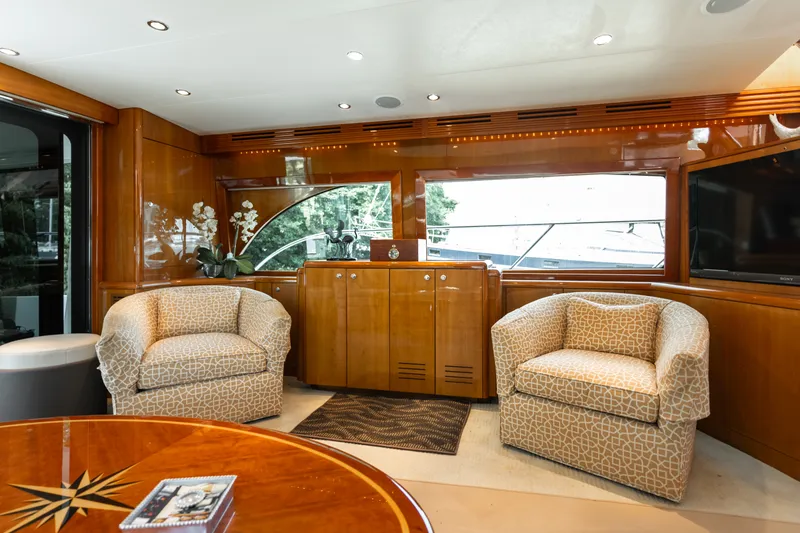 Slide: The Image of The interior of a 2008 Hatteras 64 Motor Yacht features two upholstered chairs and a wooden cabinet. - 26