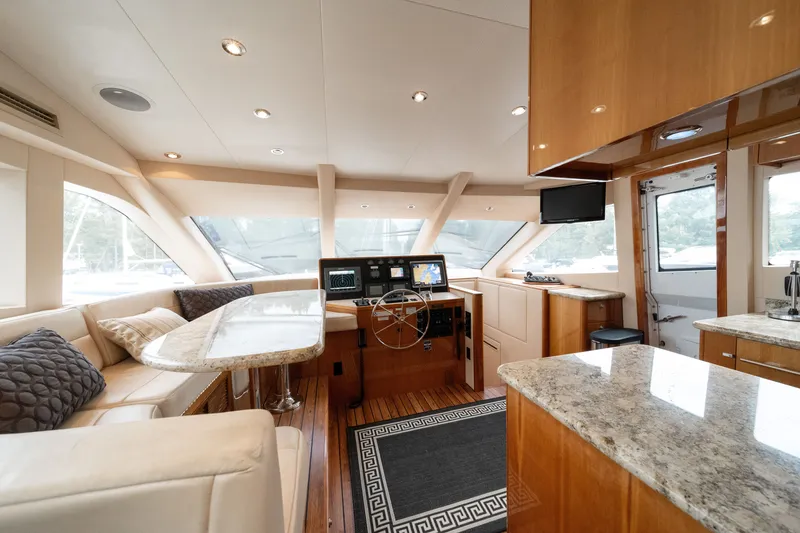 Slide: The Image of The interior of a 2008 Hatteras 64 Motor Yacht features an elegant seating area, wood flooring, and modern navigation equipment. - 48