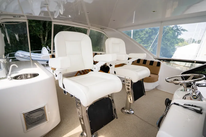 Slide: The Image of The image shows the helm of a 2008 Hatteras 64 Motor Yacht with two white captain's chairs. - 44