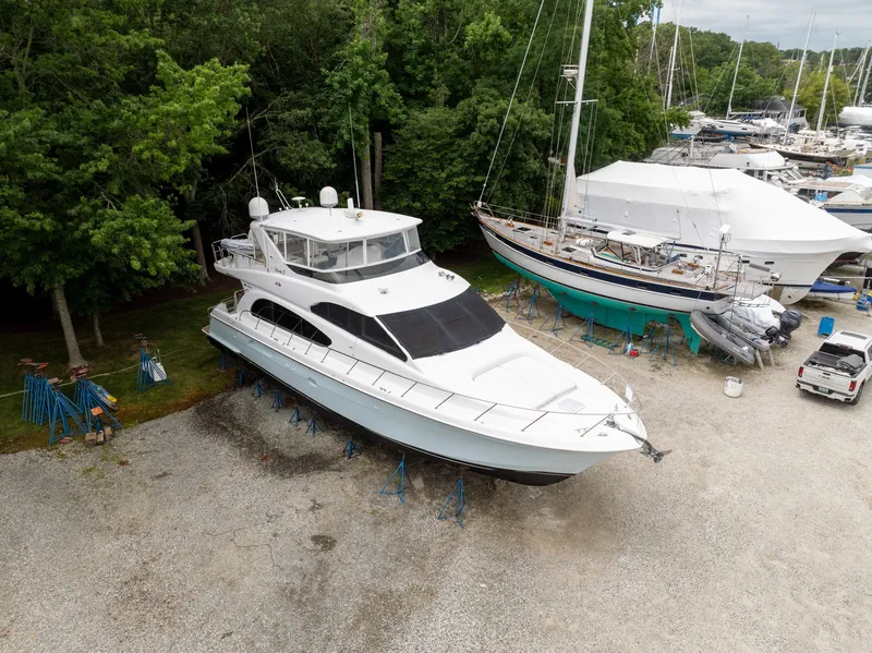 Slide: The Image of A 2008 Hatteras 64 Motor Yacht is on a dry dock, surrounded by trees and other boats. - 1