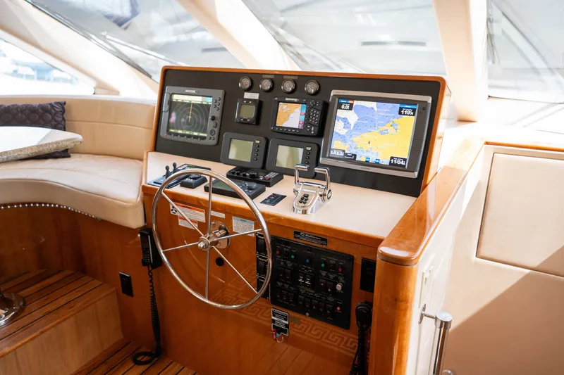 Slide: The Image of The cockpit of a 2008 Hatteras 64 Motor Yacht with modern navigation systems and a wooden steering wheel. - 29