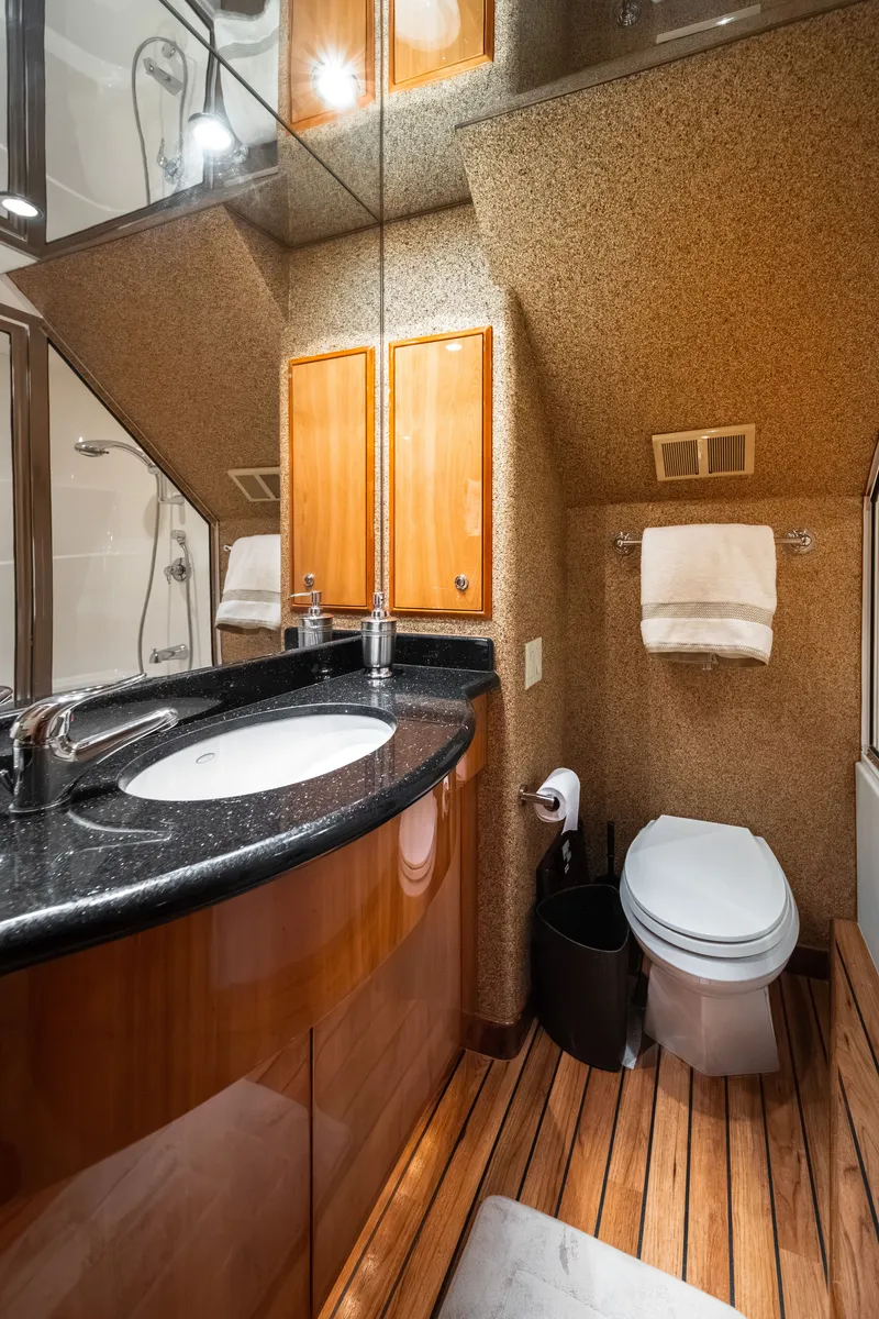 Slide: The Image of Luxurious bathroom with wood flooring, sink, toilet, and towel rack in a Hatteras 64 Motor Yacht. - 22