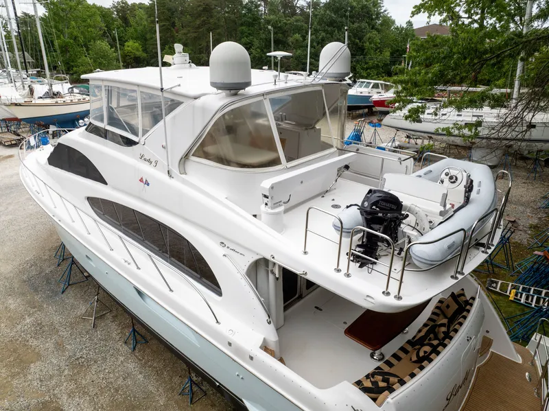 Slide: The Image of A luxurious 2008 Hatteras 64 Motor Yacht is on land. It features a spacious upper deck and a dinghy. - 7