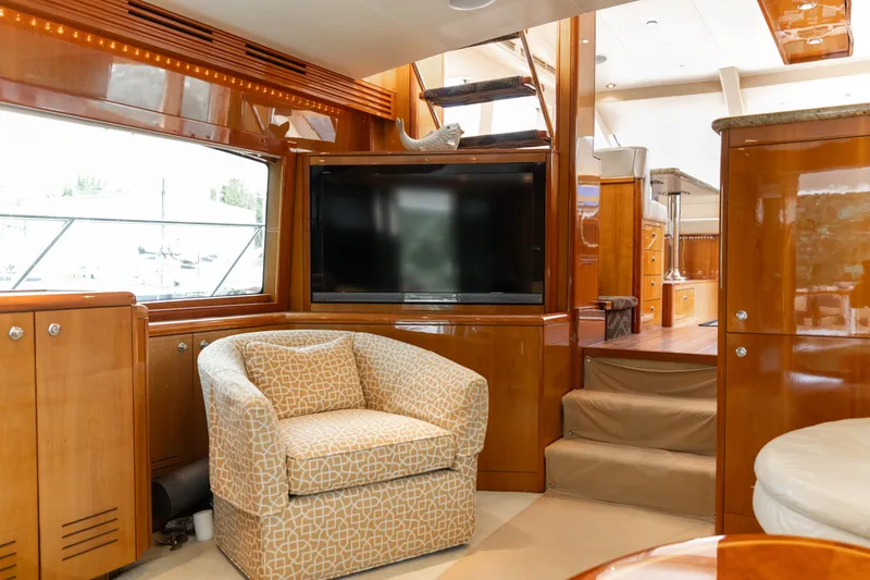 Slide: The Image of Interior of a 2008 Hatteras 64 Motor Yacht featuring a cozy armchair and a large TV. - 28