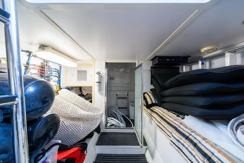 Slide: The Image of The interior of a 2008 Hatteras 64 Motor Yacht shows a well-organized storage area with fenders, hoses, and stacked cushions. - 12