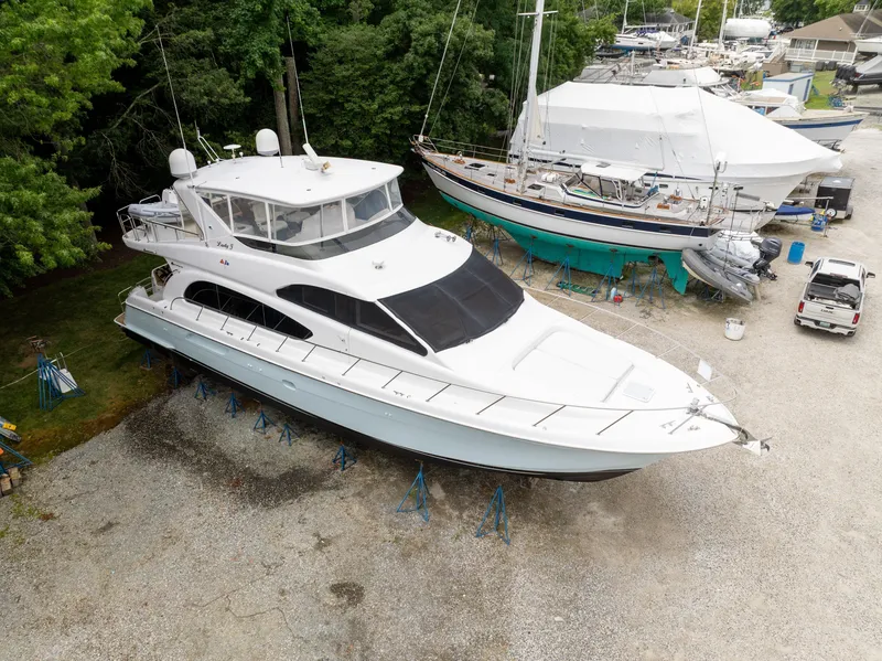 Slide: The Image of A 2008 Hatteras 64 Motor Yacht is on a dry dock, surrounded by trees and other boats. - 2